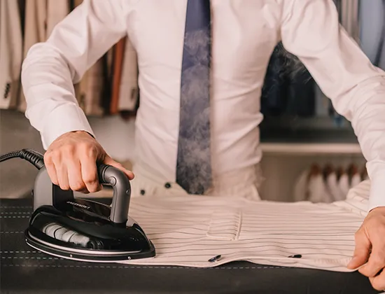 Laurastar S PURE XTRA in Orchid Hush colour, close-up of the 3D soleplate iron gliding across a delicate fabric on the active board, demonstrating fabric protection and crease prevention with efficient steam ironing.