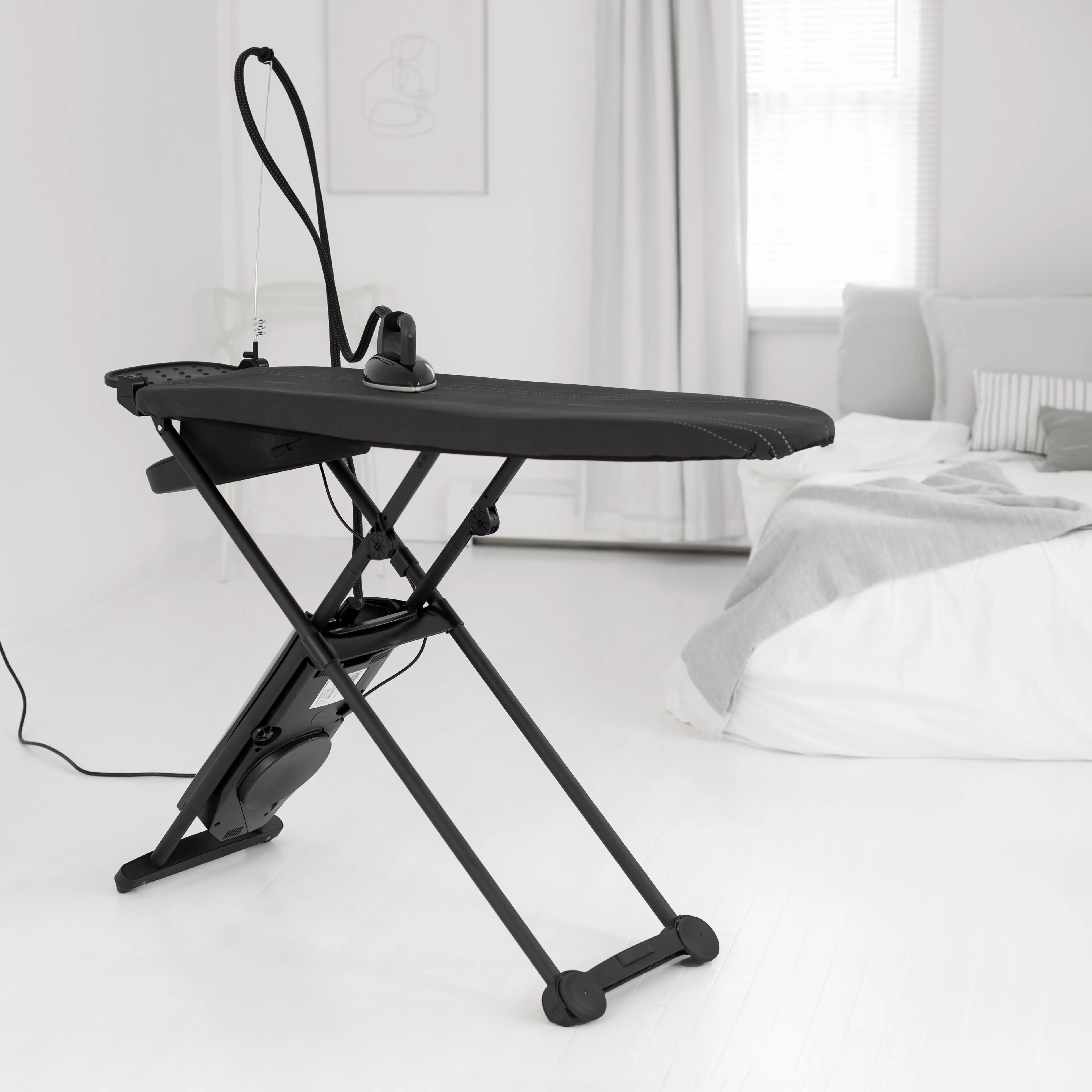 A Laurastar all-in-one ironing system displayed in a contemporary home setting, with the active ironing board inflated to show the ActivAir technology air cushion, and steam rising from the professional iron, representing luxury laundry care in the UK.