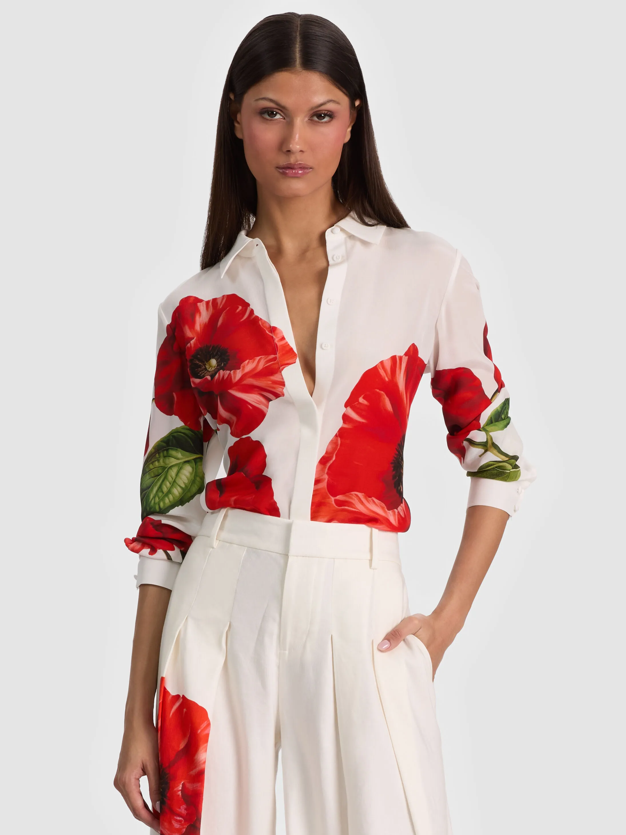 A woman wearing the ALICE + OLIVIA Willa Silk Blouse in floral print, paired with tailored trousers — a perfect example of a dressy casual outfit with feminine polish and refined ease.