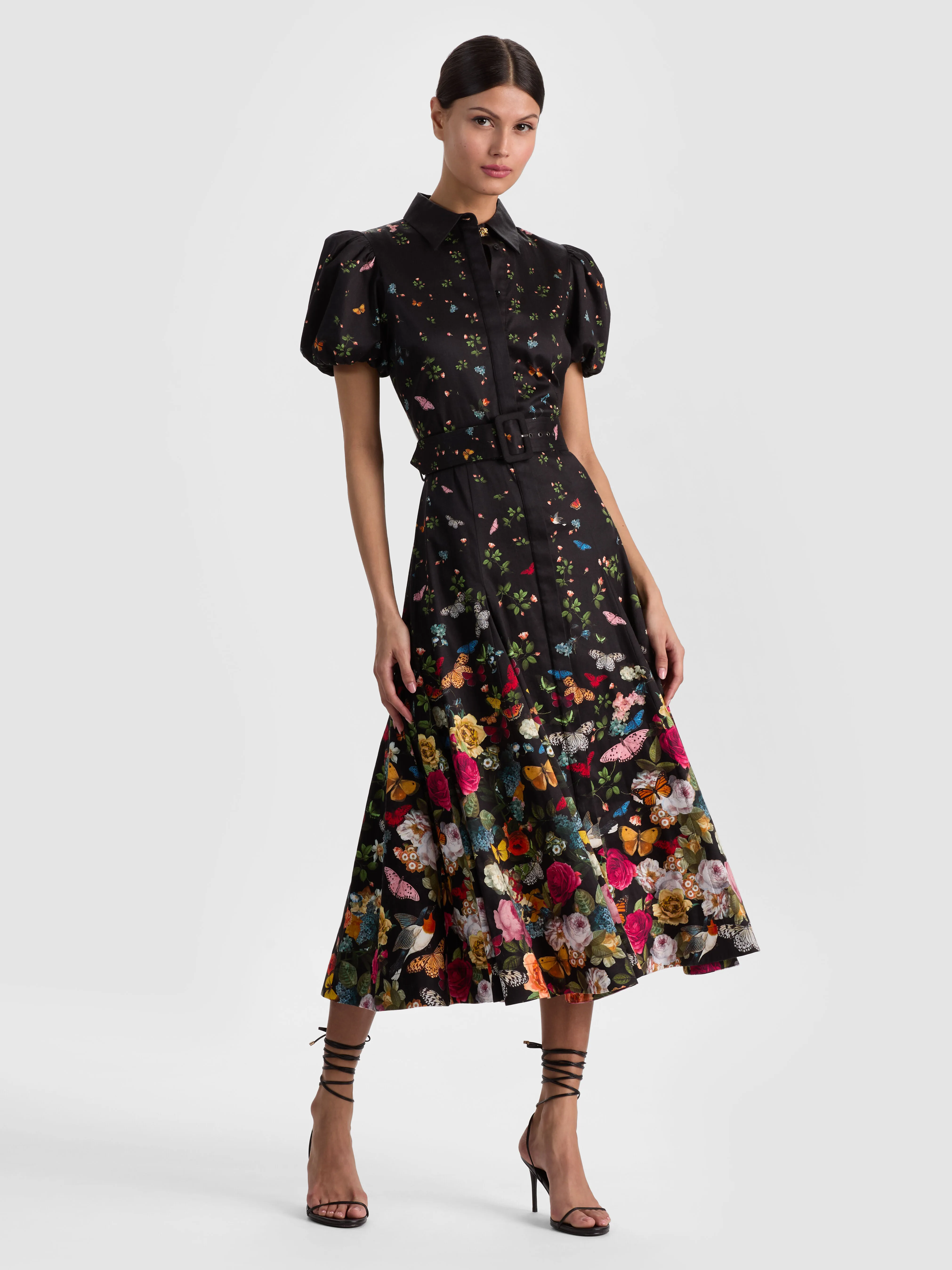 The ALICE + OLIVIA HENRIETTA BELTED MIDI DRESS in printed cotton sateen with a belted waist and full skirt, styled for a polished layered look.