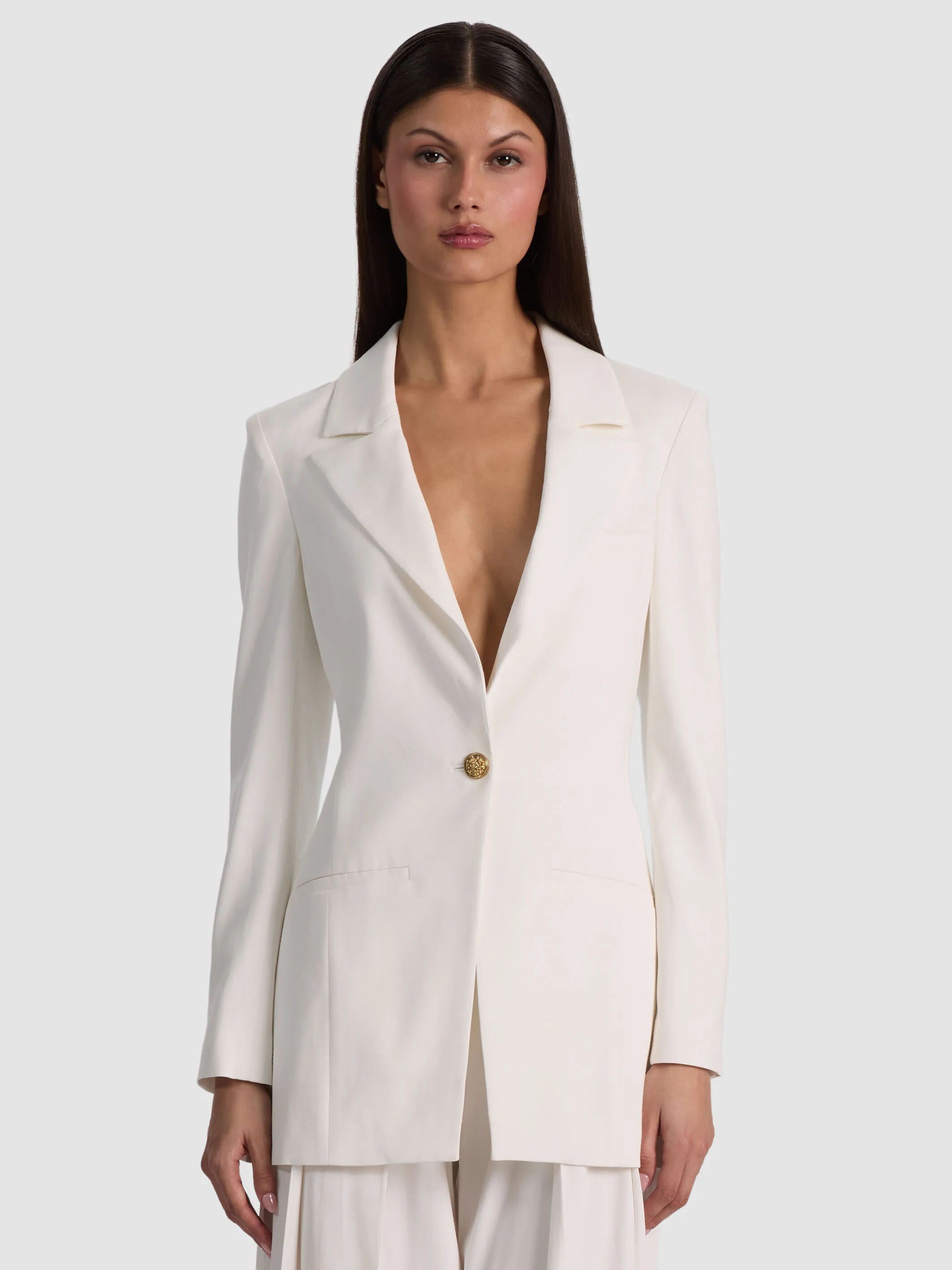 A woman styled in a dressy casual women's outfit featuring the ALICE + OLIVIA Hope Fitted Blazer in lightweight twill, paired with tailored trousers and refined flats — polished, modern, and effortlessly chic.