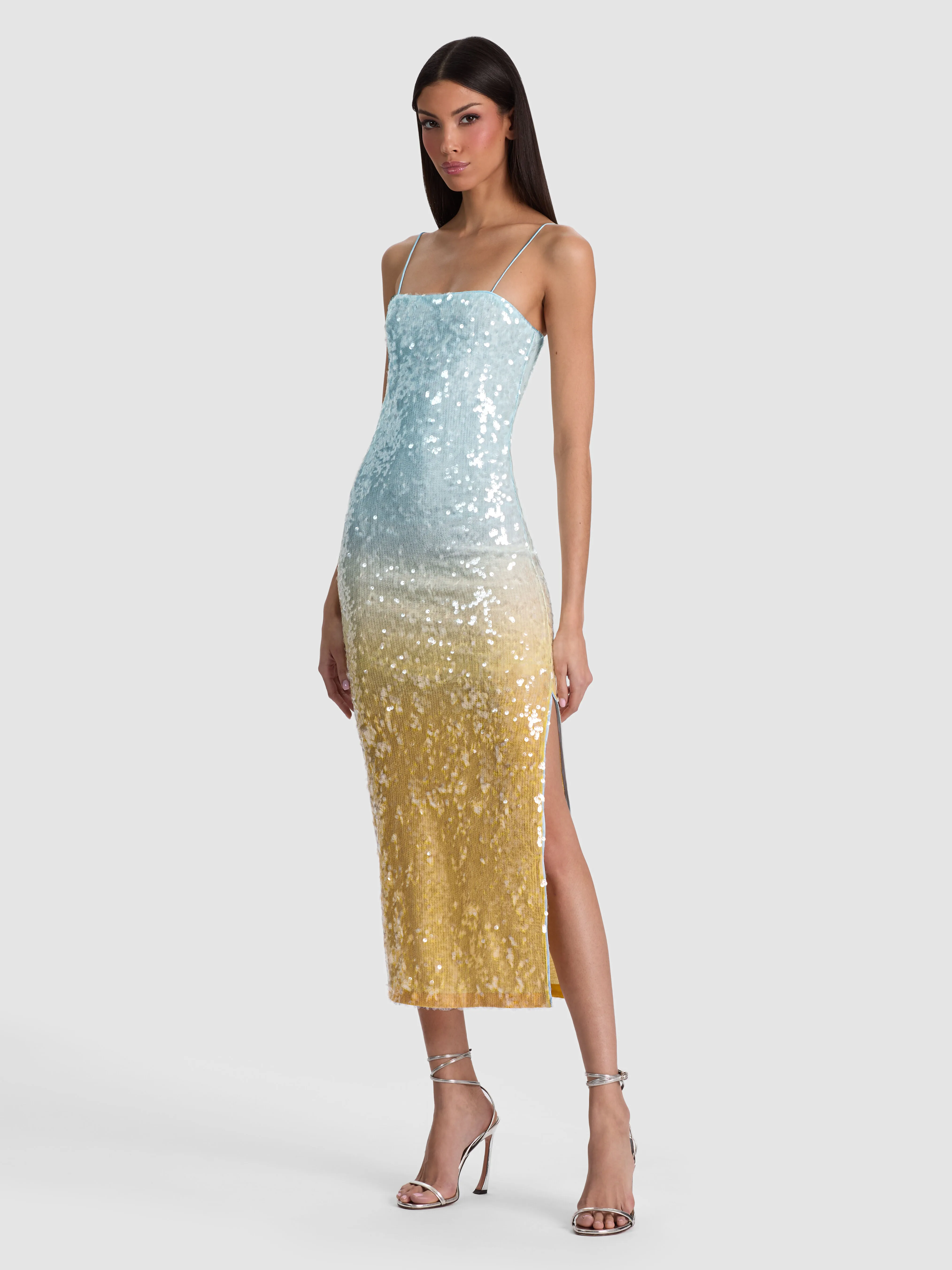 A model wearing the ALICE + OLIVIA Fifi Sequin Midi Dress in multicolored ombre sequins at a glamorous evening event, accessorized with sculptural jewelry and a sleek clutch.