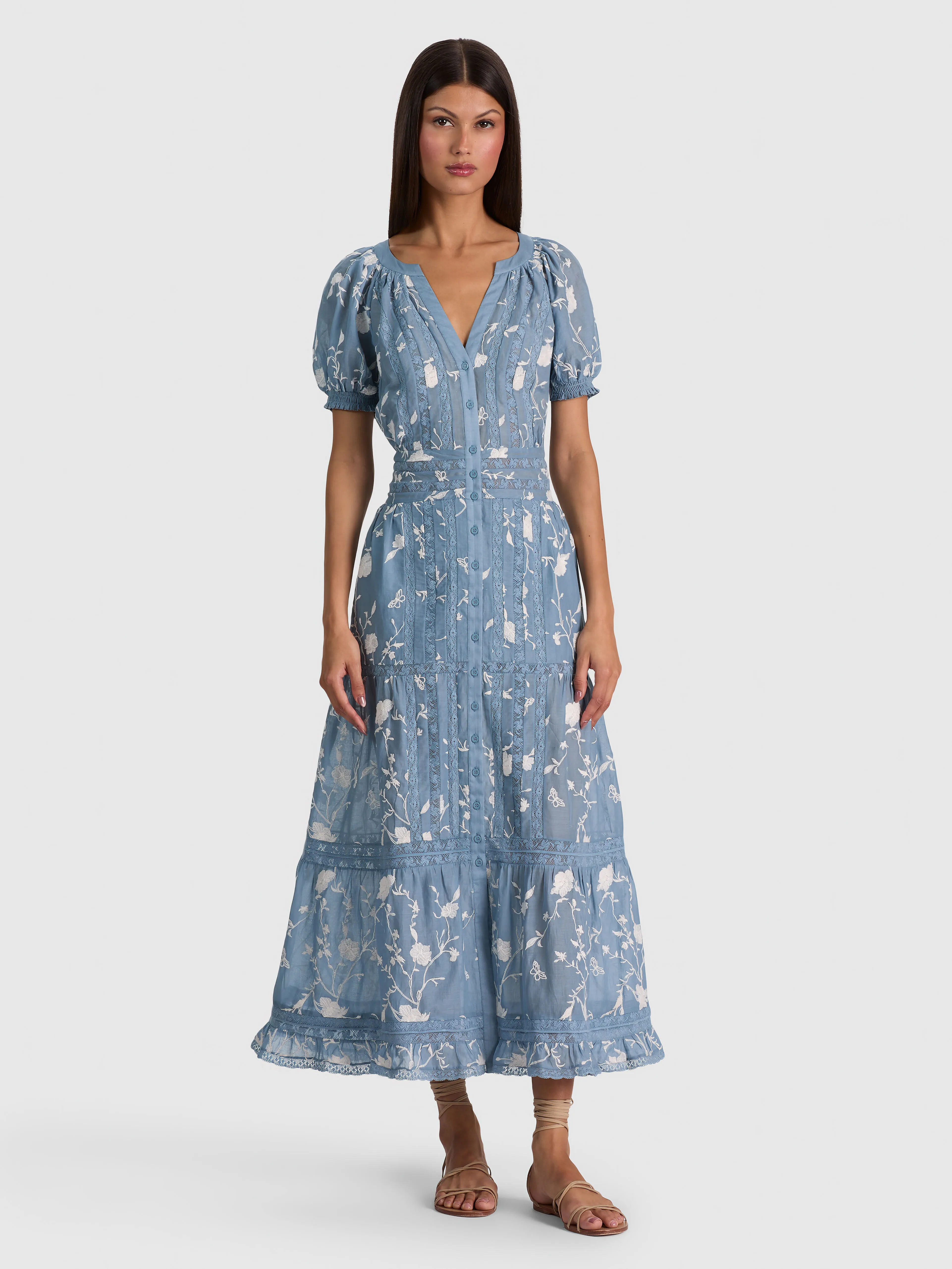 A model wearing the ALICE + OLIVIA Kathryn Midi Shirt Dress in cotton voile with puffed short sleeves and embroidered lace, styled casually with loafers.