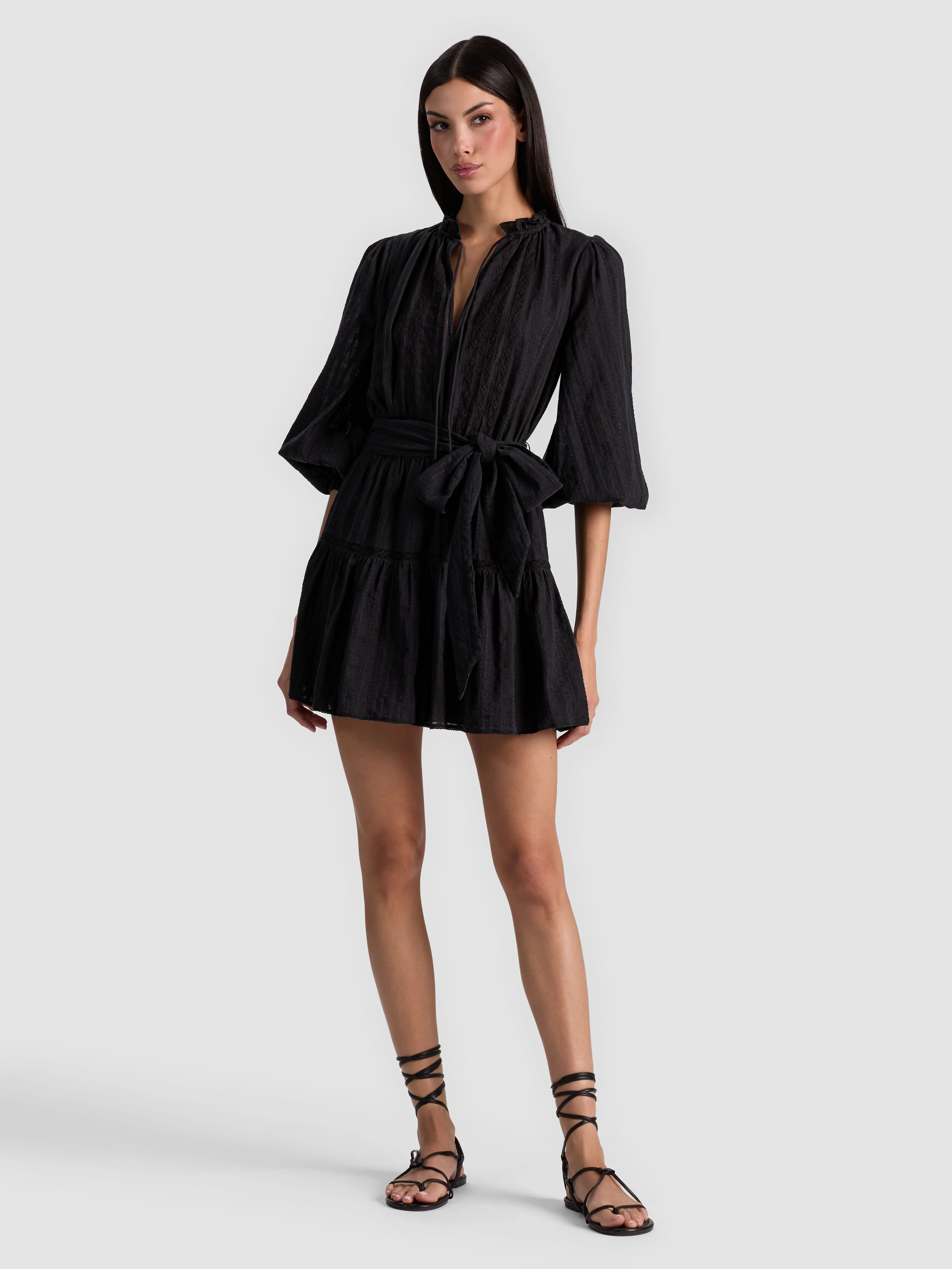 A lifestyle shot of a model wearing the Sadie Mini Shirt Dress in black, styled casually with chunky boots and a denim jacket for a relaxed weekend look.
