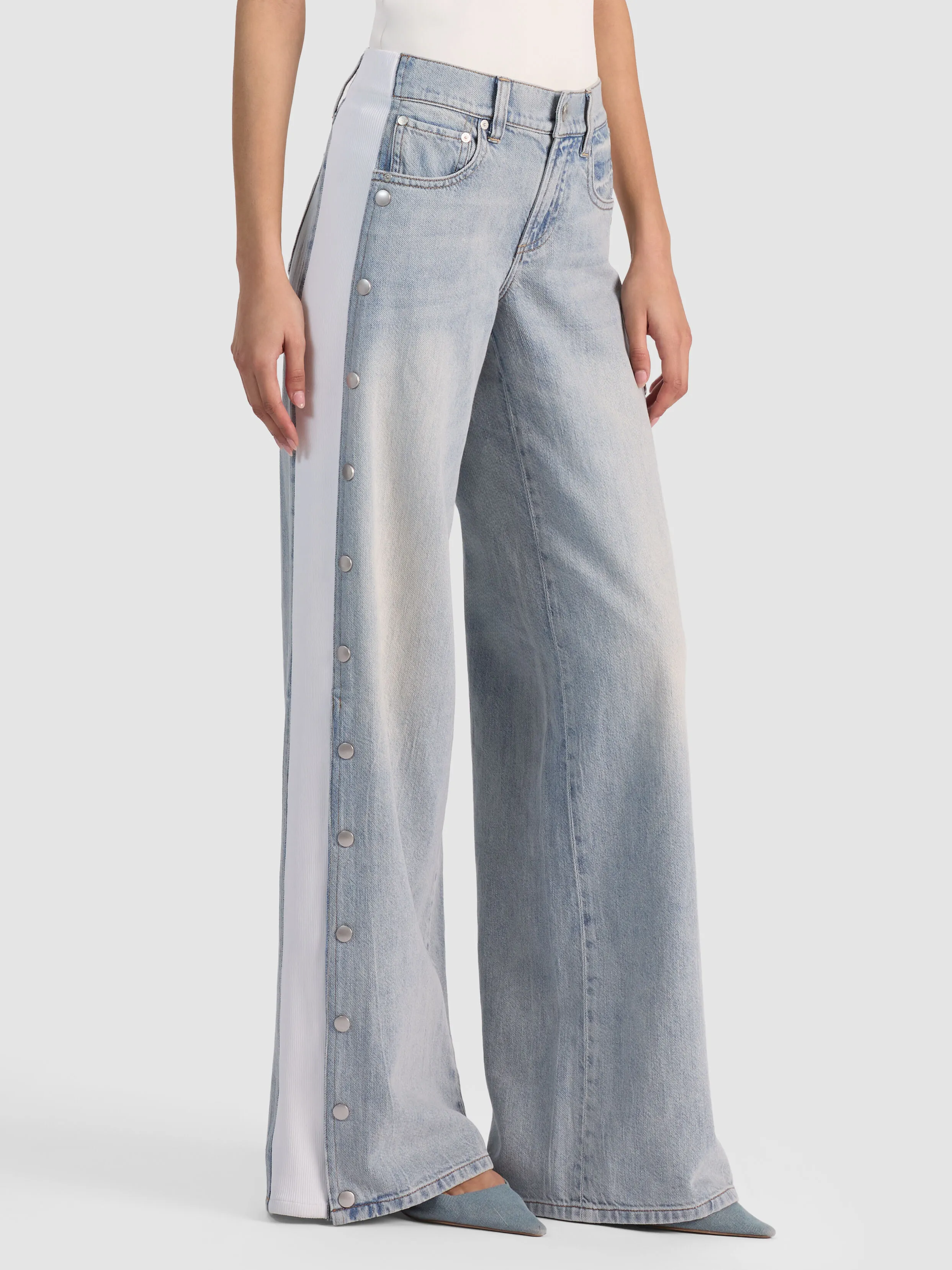 A full-length shot of the ALICE + OLIVIA Amazing Snap Jean showing the mixed media side panels with snap closures at the hem, representing the split-hem and modern denim details trend for 2026.