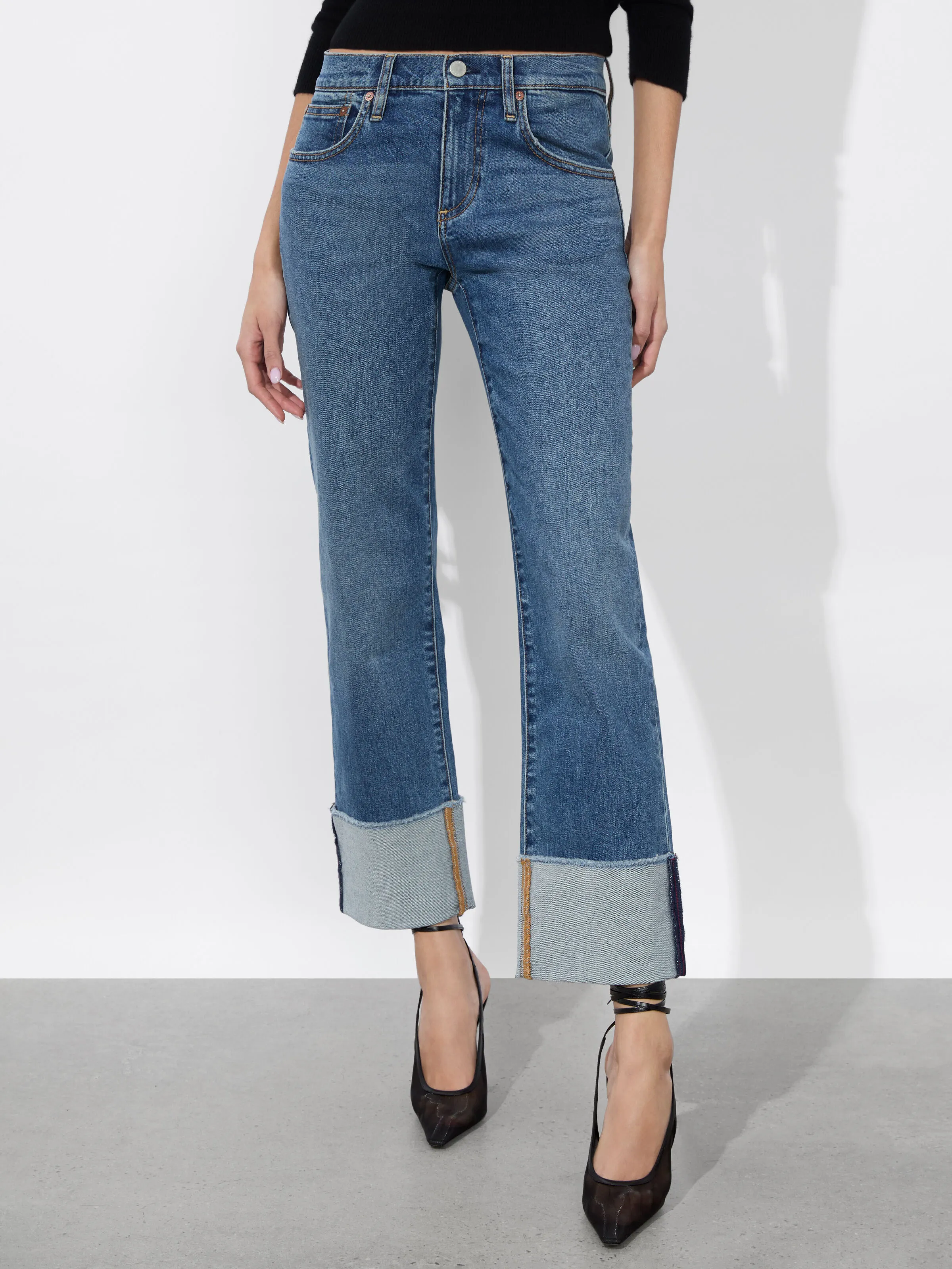 A full-length shot of a woman wearing the ALICE + OLIVIA Abilene Cuffed Jean with raw hem cuffs and a skinny leg silhouette, representing the cuffed and structured denim trend for 2026.