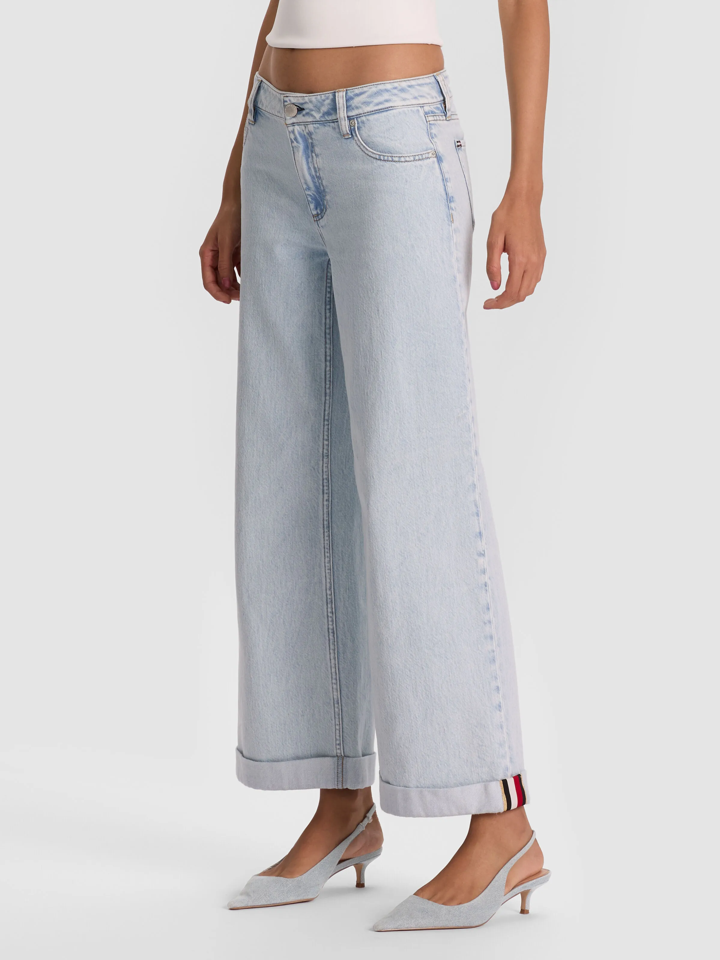 A full-length shot of a woman wearing the ALICE + OLIVIA Duncan Jean in a light indigo wash, showcasing the fresh icy-blue denim trend for 2026.