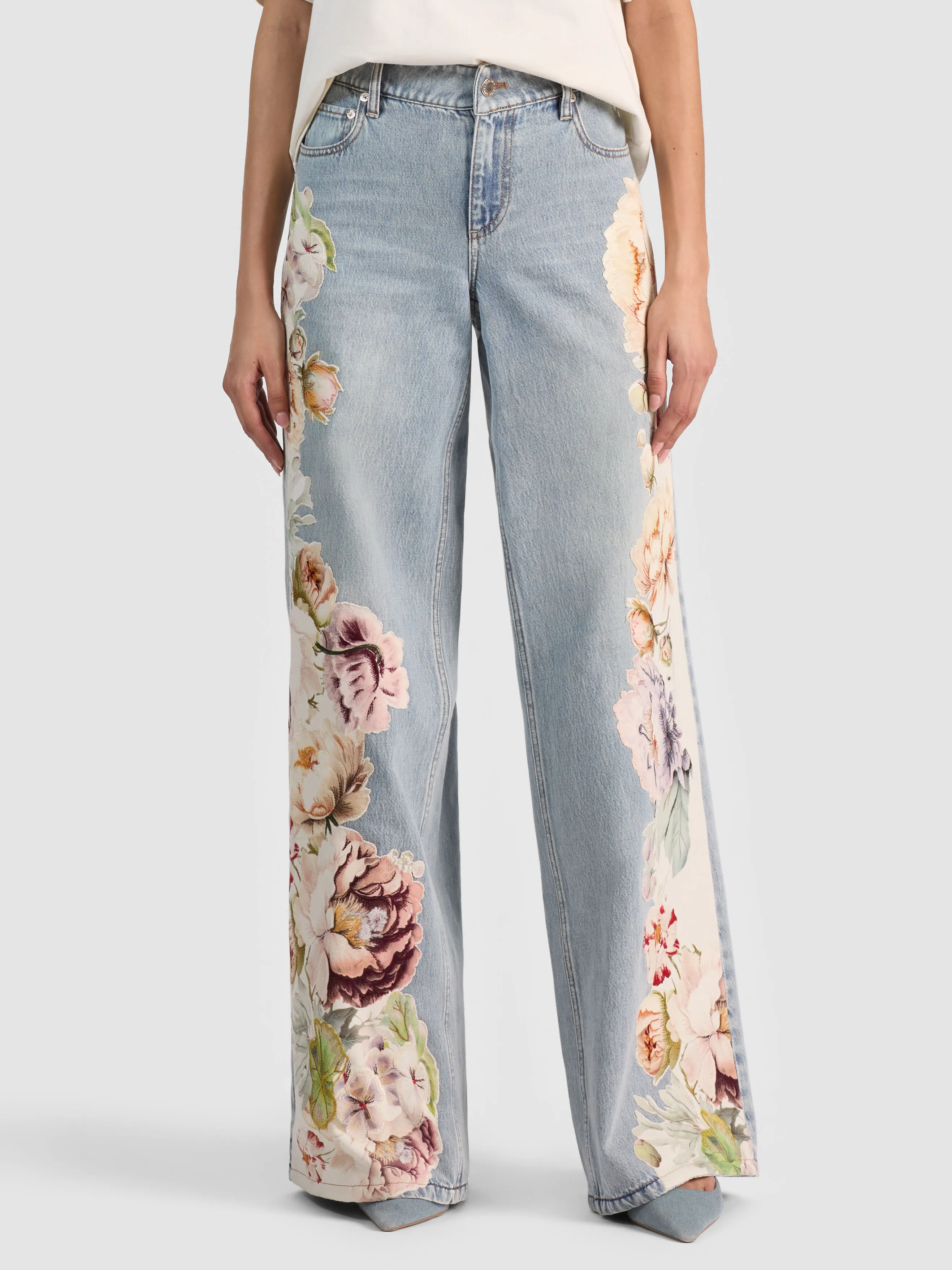 Full-body shot of a model wearing the ALICE + OLIVIA Amazing Embroidered Jean in a sierra vintage multi floral embroidered wide-leg silhouette, styled head to toe, representing the top 2026 denim trends.