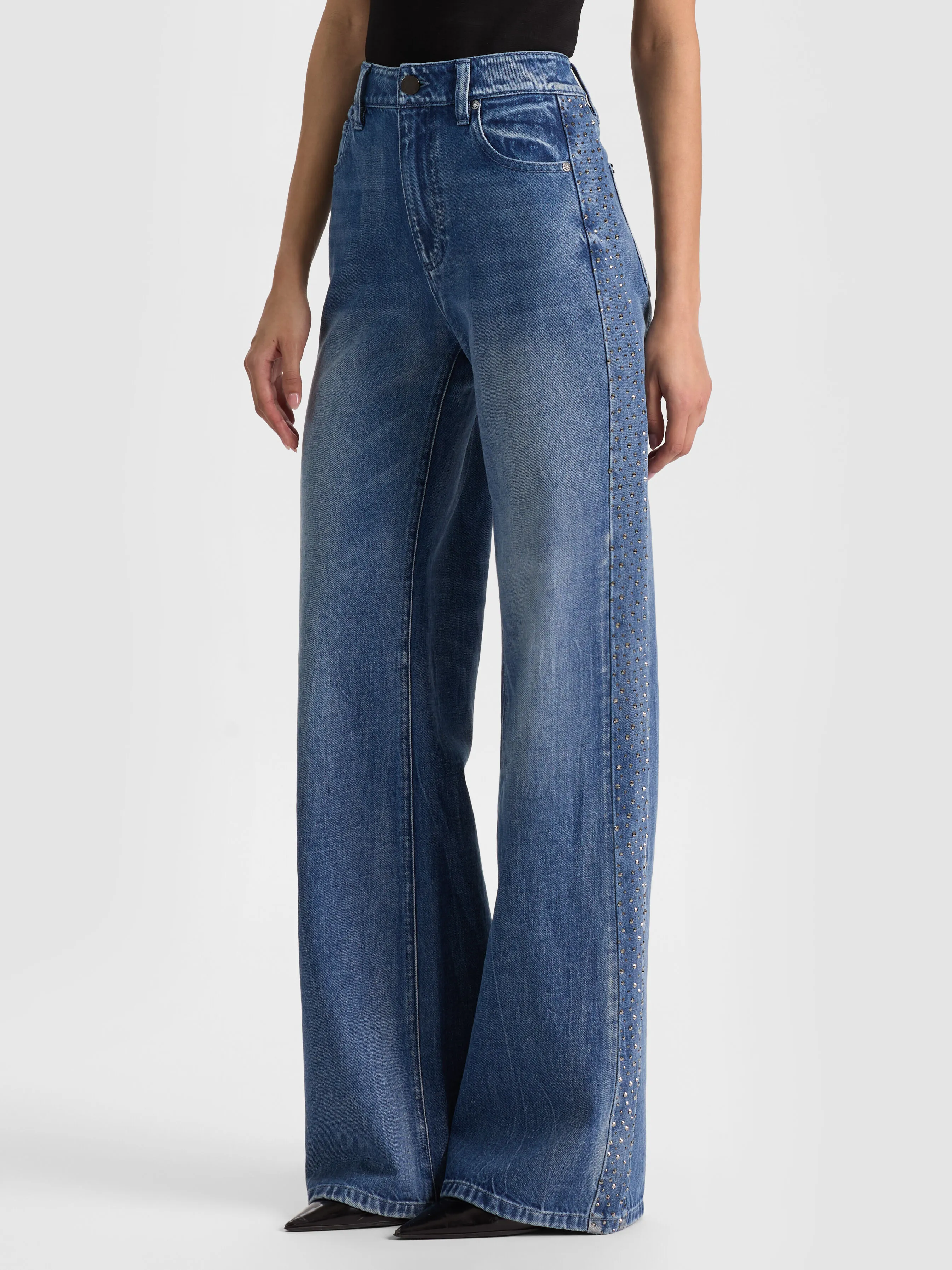 A full-body editorial lineup showcasing multiple types of ALICE + OLIVIA wide-leg jeans including the Chic Embellished Jean, Amazing Snap Jean, Beautiful Jean, and Whit Ultra High Button Front Jean, highlighting classic, high-rise, low-rise, and embellished styles.