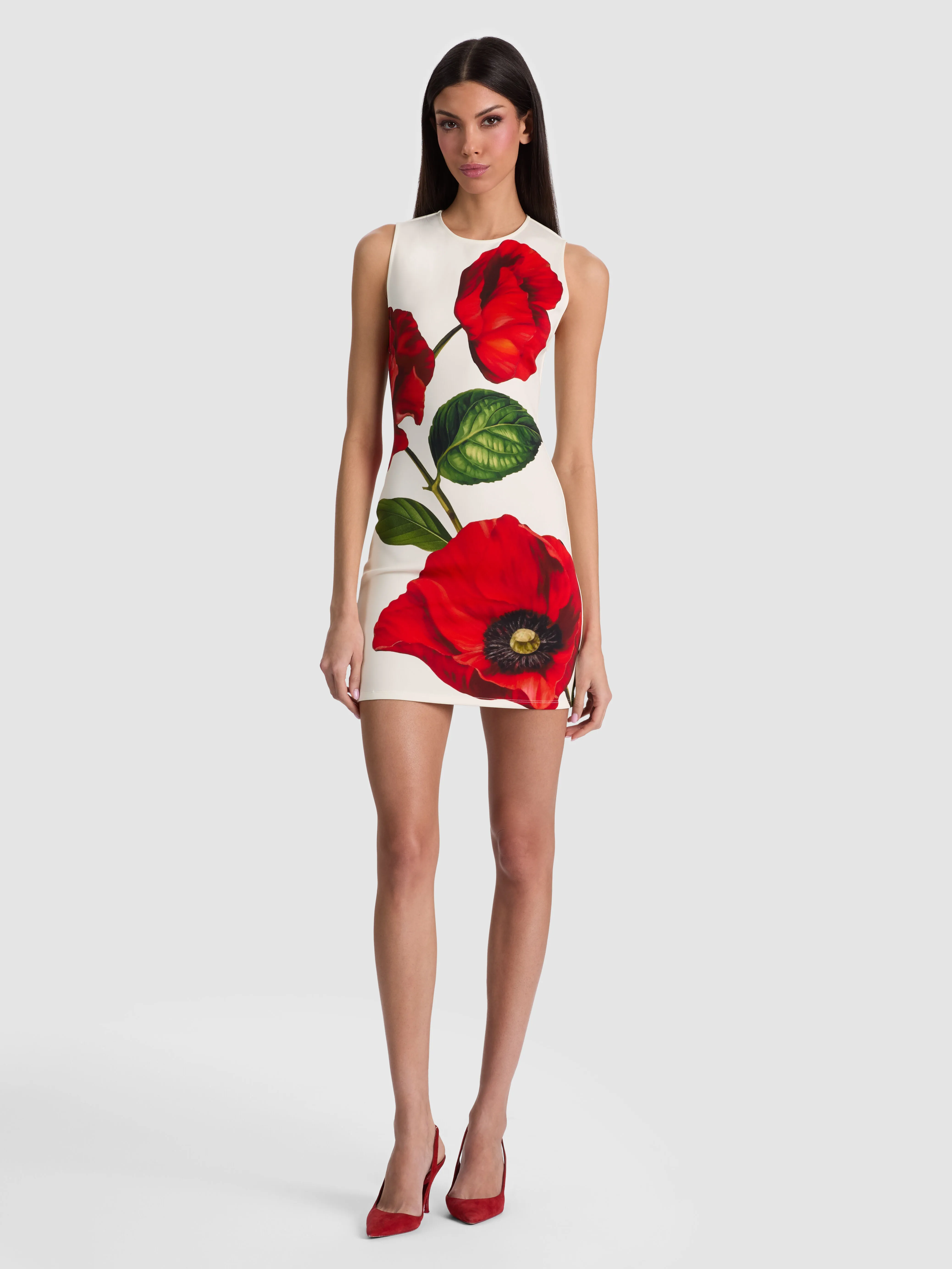 A woman wearing the Wynell Fitted Mini Dress in vibrant floral scuba fabric, standing confidently outside a lit-up city restaurant at night, heels and minimal jewelry.