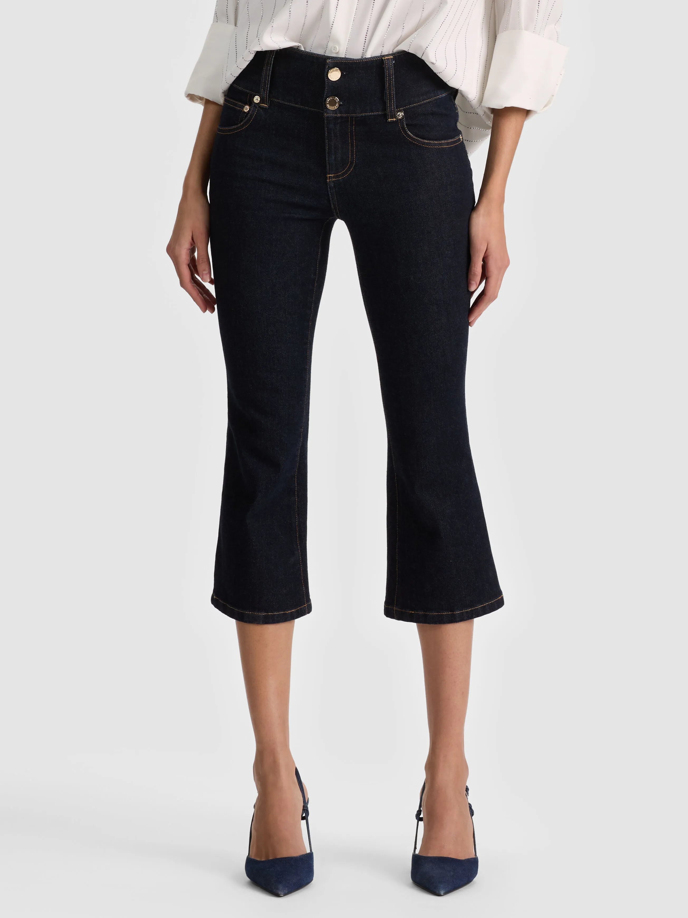 A full-length lifestyle shot of a woman wearing the KAI LOW RISE CAPRI JEAN, showcasing the cropped capri-length silhouette styled with statement sandals, highlighting the tailored and minimalist cropped denim trend for 2026.